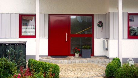 Neue Fenster und Türen mit Qualität. perfecta hält Wort – seit 45 Jahren. Haus mit roter Eingangstür und Glasfenster von perfecta Fenster