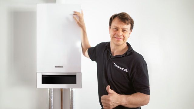 Thermondo - So geht Heizungswechsel heute Thermondo Monteur steht neben Heizungsanlage und zeigt die Daumen hoch