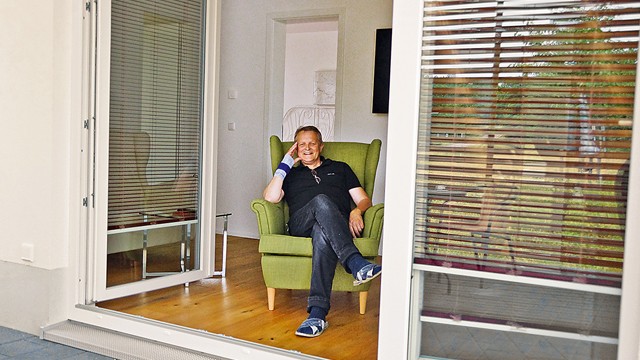 Joachim Höfling in einem seiner Minihäuser Mann auf Sessel im Minihaus