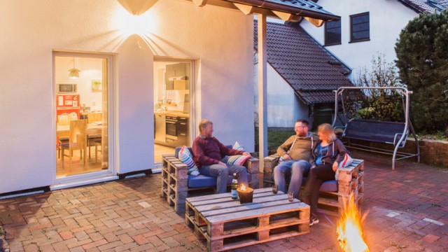 Familie sitzt auf der Terrasse ihres Gartens in Palettenmöbeln