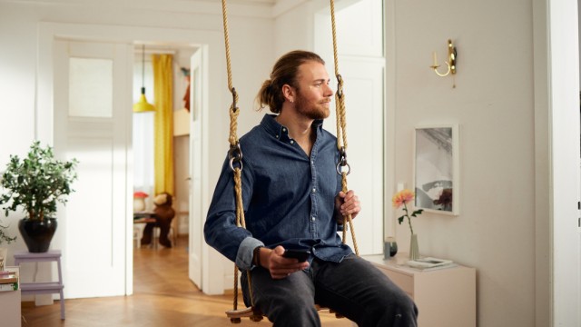 Ein Mann schaukelt und informiert sich auf seinem Handy zum Mietvertrag