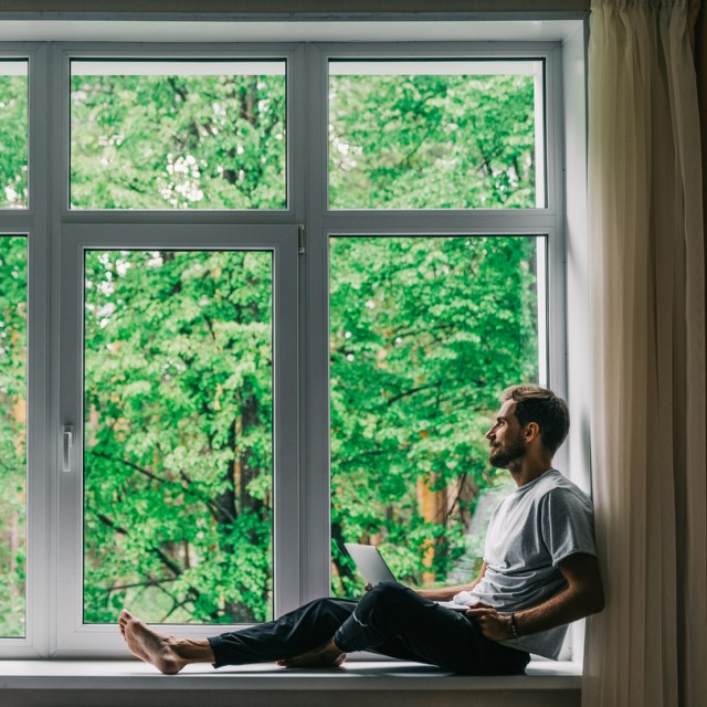 Ein Mann sitzt am Fenster und vergleicht auf seinem Laptop die Zinsen verschiedener Bauspardarlehen Ein Mann sitzt am Fenster und vergleicht auf seinem Laptop die Zinsen verschiedener Bauspardarlehen