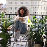 Eine junge Frau sitzt auf dem Balkon ihrer ersten eigenen Wohnung