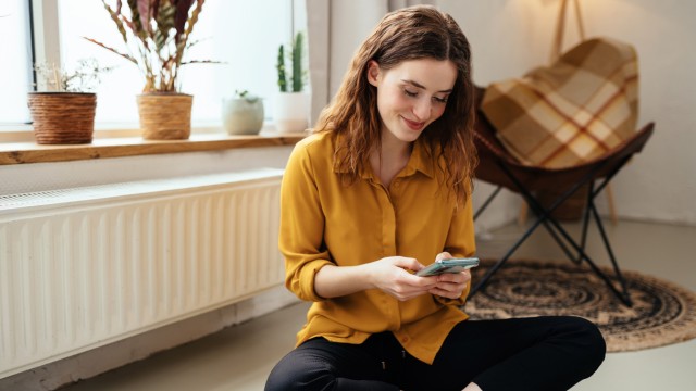 Eine junge Frau informiert sich auf ihrem Smartphone zum Thema Eigenkapital