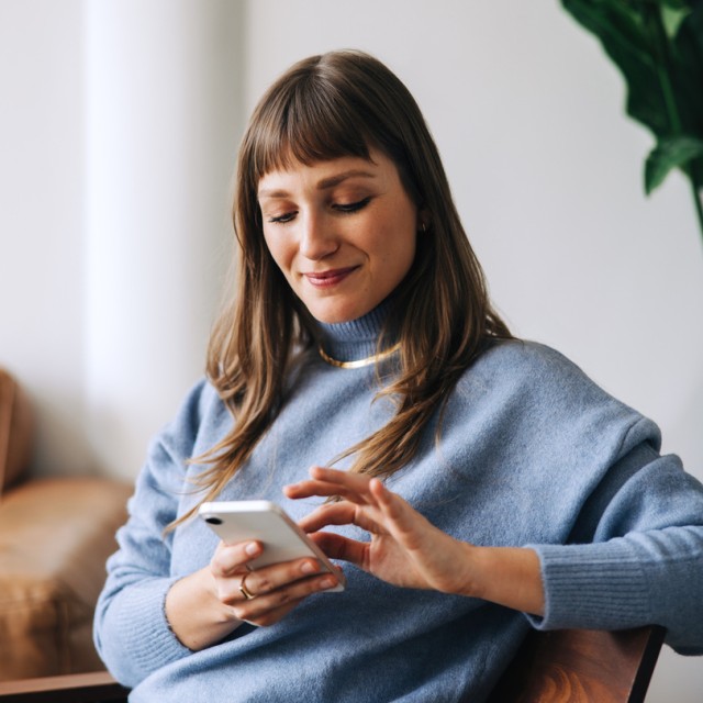 Eine Frau informiert sich auf dem Smartphone zur Eigenheimrente