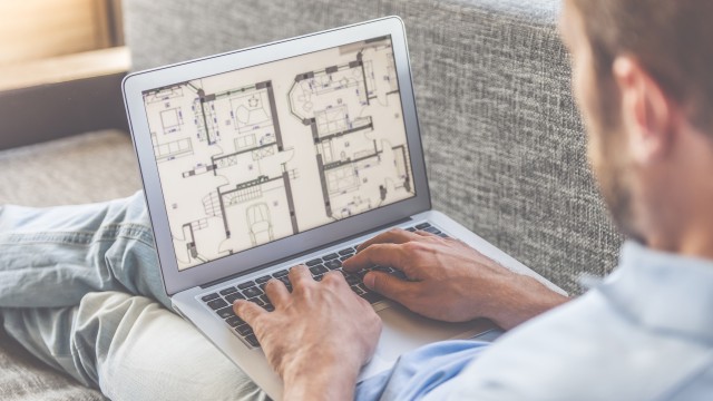 Mann schaut sich den Grundriss einer Immobilie auf seinem Laptop an
