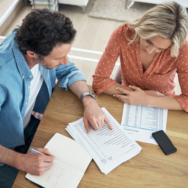 Ein Mann und eine Frau sitzen am Tisch und berechnen die Konditionen für ein Forward-Darlehen Ein Mann und eine Frau sitzen am Tisch und berechnen die Konditionen für ein Forward-Darlehen