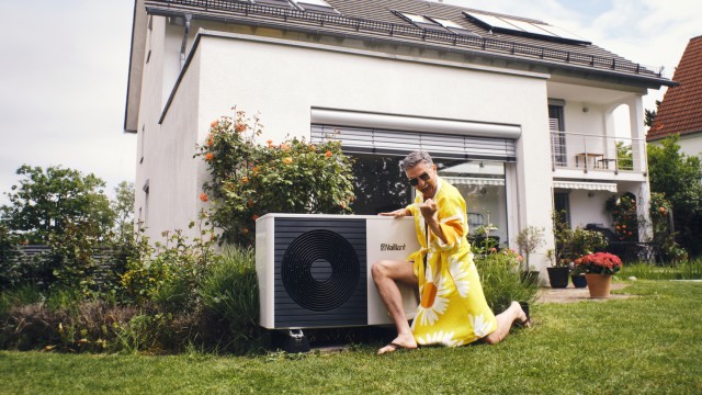 Wüstenrot Web-Seminar junge Frau im gelben Kleid lässt sich auf einem Hausdach den Wind durch die Haare wehen