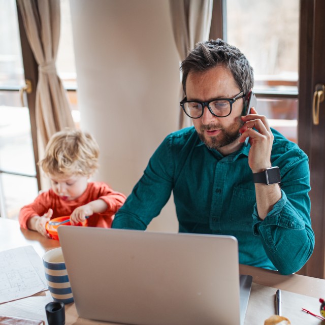 Ein Mann sitzt am Laptop und spricht telefonisch mit einem Berater zur Rechtsschutzversicherung
