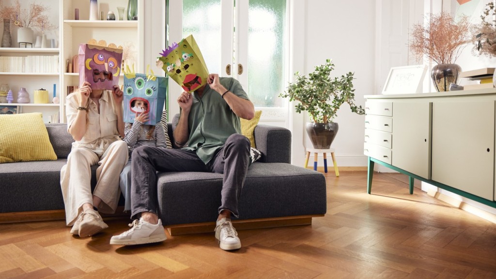 Eine junge Familie trägt lustige Masken und tütet Bausparförderungen für die eigene Tochter ein