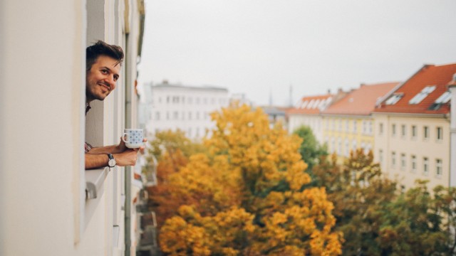 Ein Mann schaut aus dem Fenster einer Wohnung, die er mit einem Immobilienkredit kaufen möchte Ein Mann schaut aus dem Fenster einer Wohnung, die er mit einem Immobilienkredit kaufen möchte