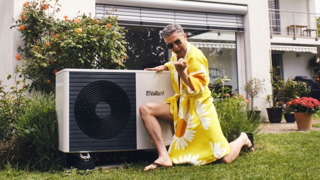 Ein Mann im Garten feiert sein modernisiertes Zuhause, das er mit einem Bausparvertrag finanziert hat