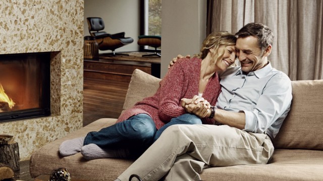 Ein Paar sitzt auf der Couch und freut sich über die Zinssicherung durch ihr Forward-Darlehen