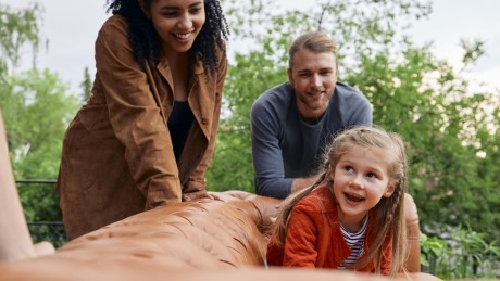 Umzugshelfer tragen Sofa auf dem ein Mädchen sitzt