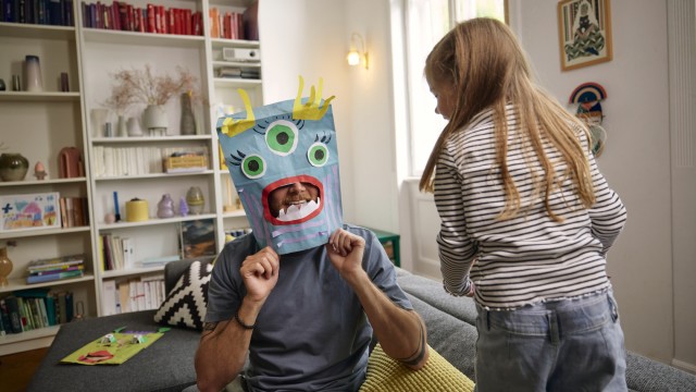 Ein Vater spielt mit seiner Tochter im Zuhause, das sie mit einer Baufinanzierung finanziert haben