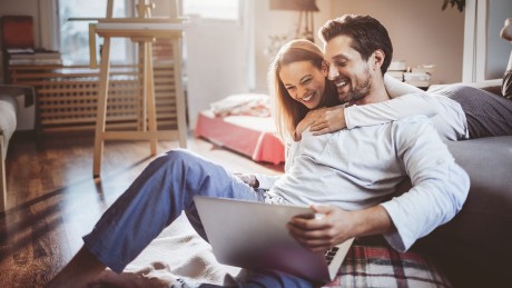 Immobiliensuche Junges Paar schaut glücklich in Laptop