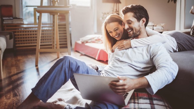 Junges Paar schaut glücklich in Laptop