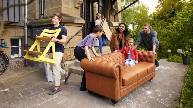Freunde tragen gemeinsam ein Sofa in die neue Wohnung, welche mit einem Bausparvertrag finanziert wurdew