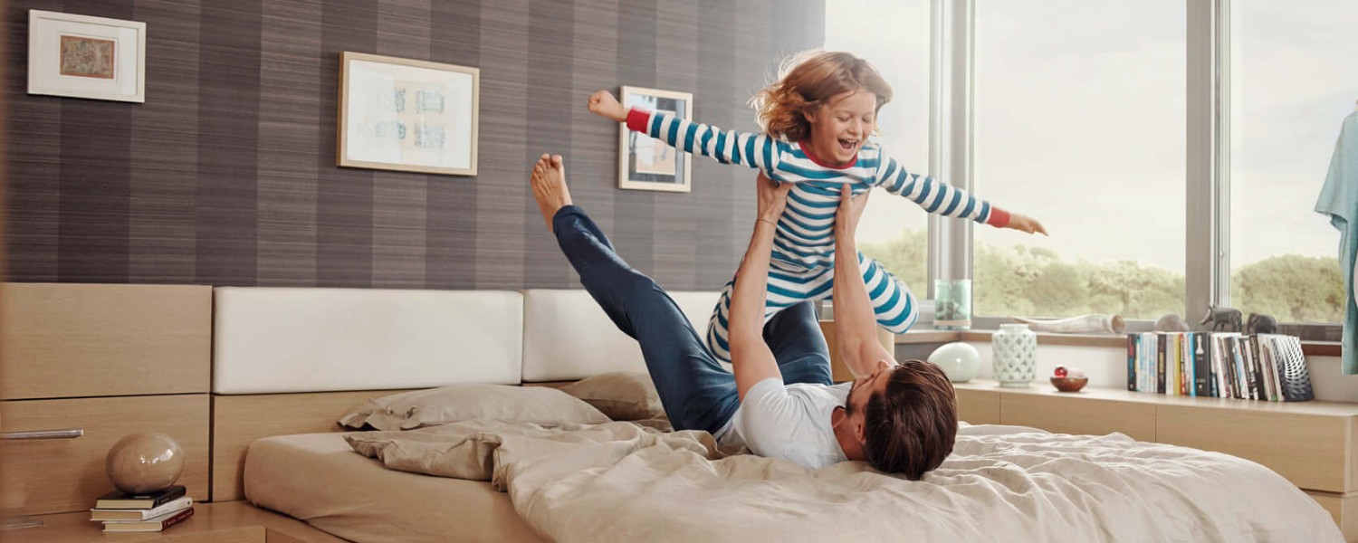 Arbeitnehmersparzulage sichern mit Wüstenrot Bausparen Vater und Tochter toben im Schlafzimmer
