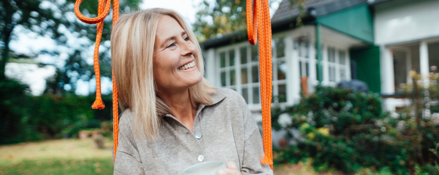 Eine Frau im Garten freut sich über eine erfolgreiche Energieberatung Eine Frau im Garten freut sich über eine erfolgreiche Energieberatung