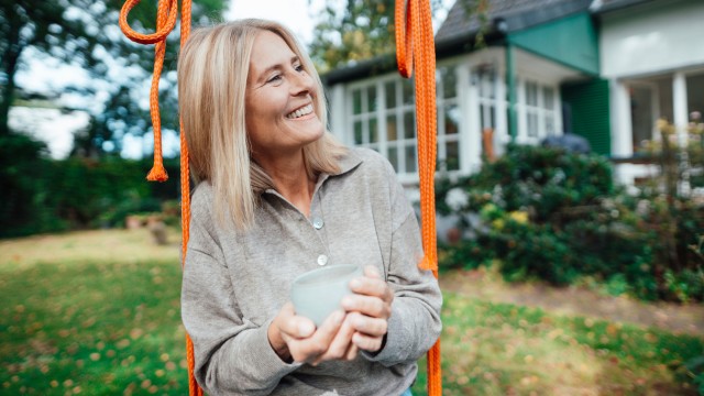 Eine Frau sitzt auf einer Schaukel im Garten und freut sich über die Ergebnisse des Haushaltsrechners Eine Frau sitzt auf einer Schaukel im Garten und freut sich über die Ergebnisse des Haushaltsrechners