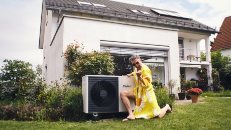 energieberatung junge Frau im gelben Kleid lässt sich auf einem Hausdach den Wind durch die Haare wehen
