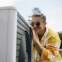 Zum Ratgeber: Energetische Sanierung Ein Mann freut sich über eine neue Wärmepumpe im Garten