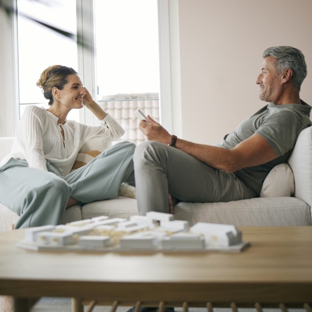 Ein Paar auf der Couch genießt die Vorteile ihrer Immobilienfinanzierung Ein Paar auf der Couch genießt die Vorteile ihrer Immobilienfinanzierung