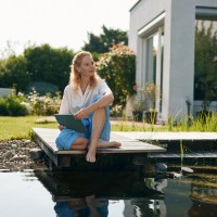 Eine Frau im Garten informiert auf ihrem Tablet zum Bausparen Eine Frau im Garten informiert auf ihrem Tablet zum Bausparen