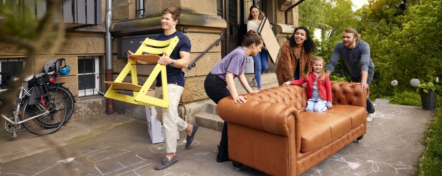 Freunde tragen gemeinsam ein Sofa in die neue Wohnung Freunde tragen gemeinsam ein Sofa in die neue Wohnung