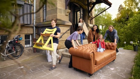 Willkommen bei Wüstenrot Freunde tragen gemeinsam ein Sofa in die neue Wohnung